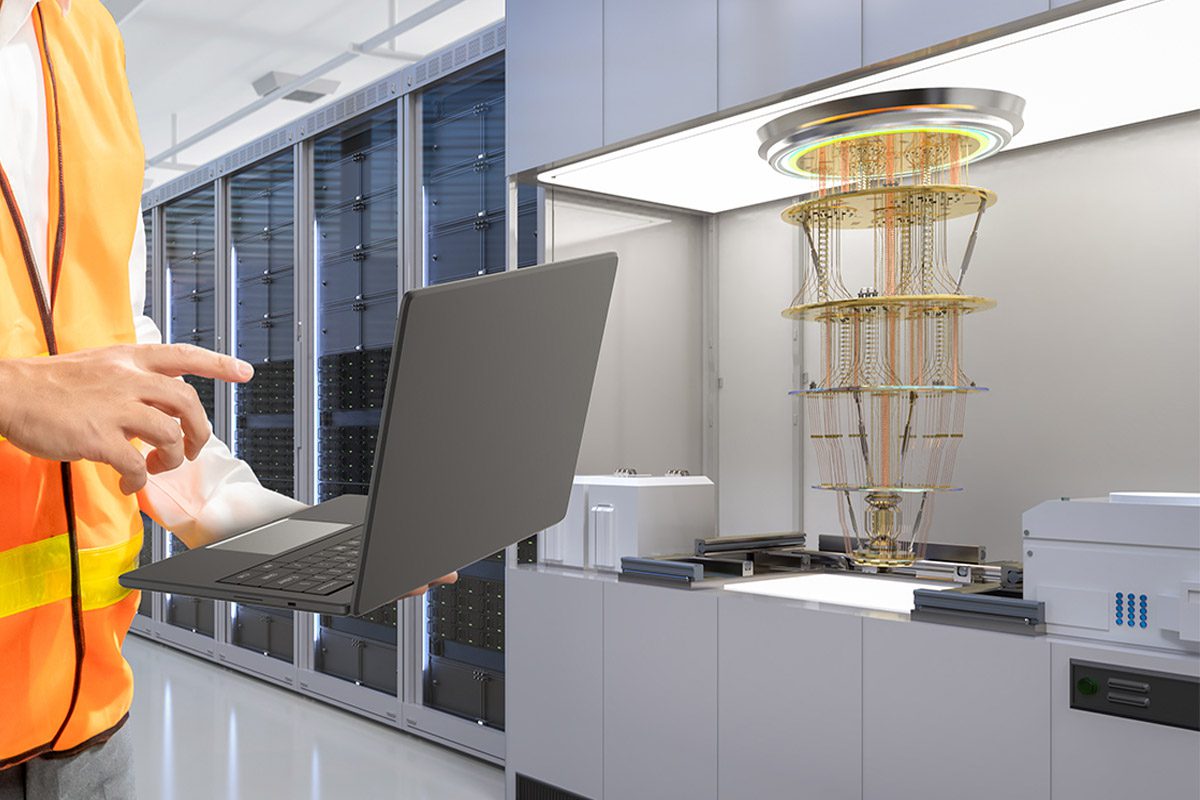 Stock image of industrial setting showing quantum computer and man holding laptop