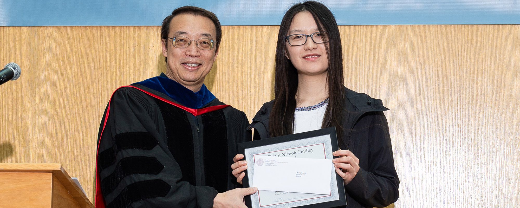 Director of AEP, Chris Xu, stands next to a graduate student holding an award
