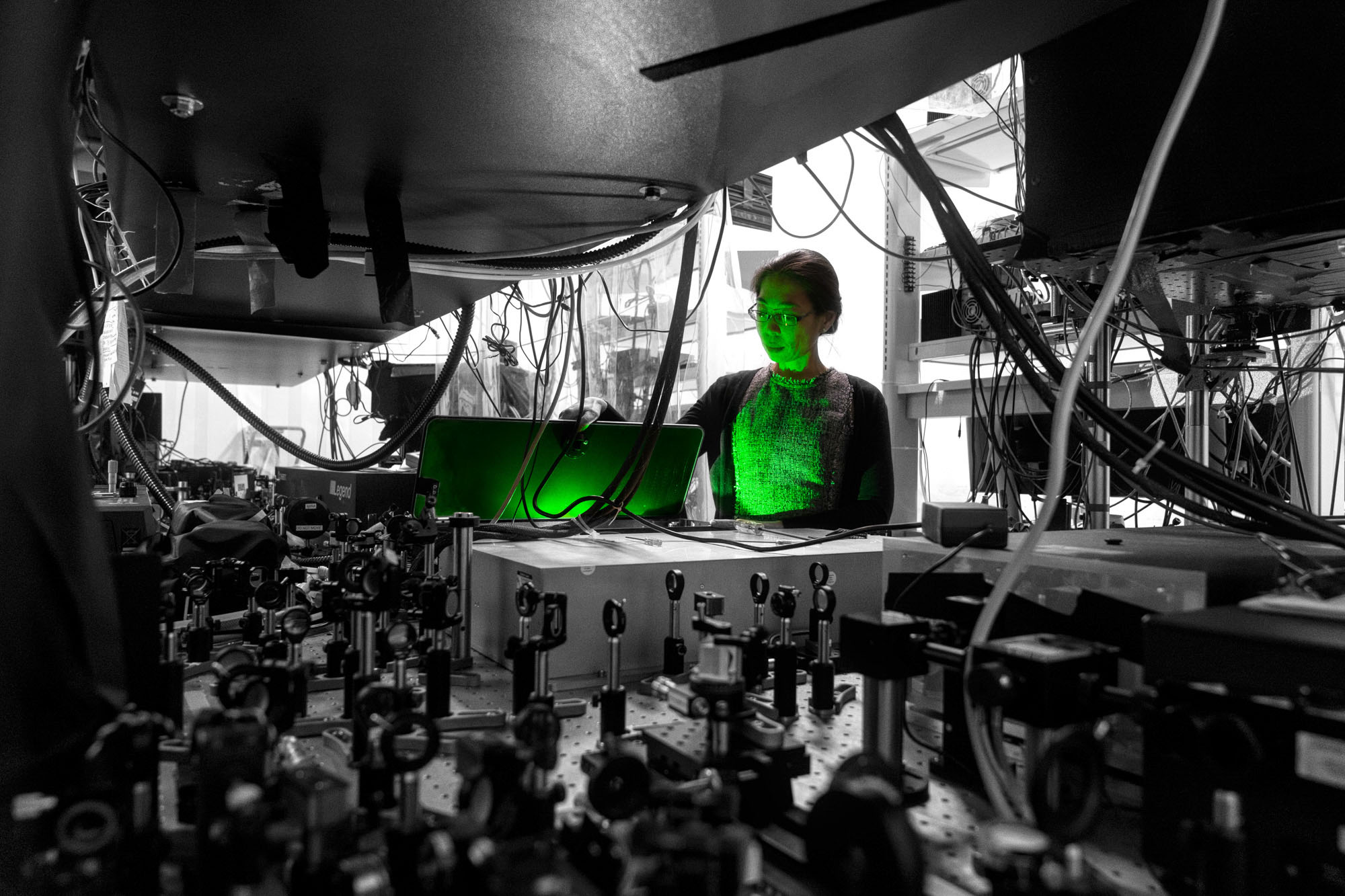 Professor Nozomi Nishimura conducts an experiment as green light reflects off her in the Schaffer-Nishimura lab.