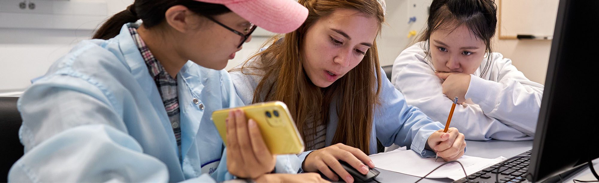Undergraduate students work together in lab with computers and calculators