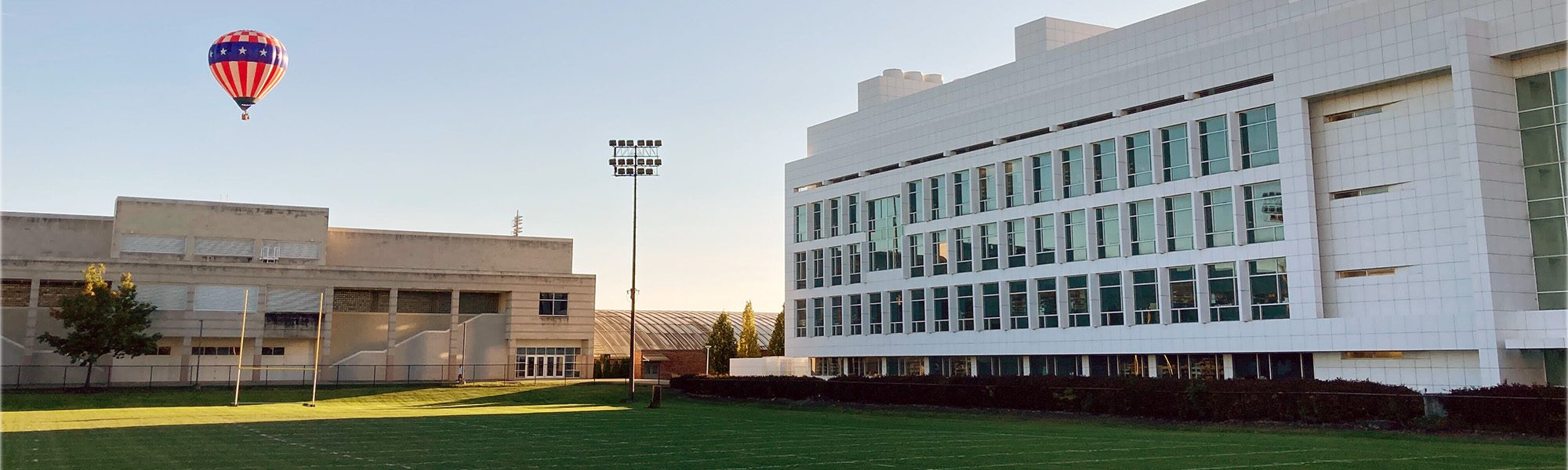 Outside view of Weill Hall and soccer field with hot air balloon in sky.