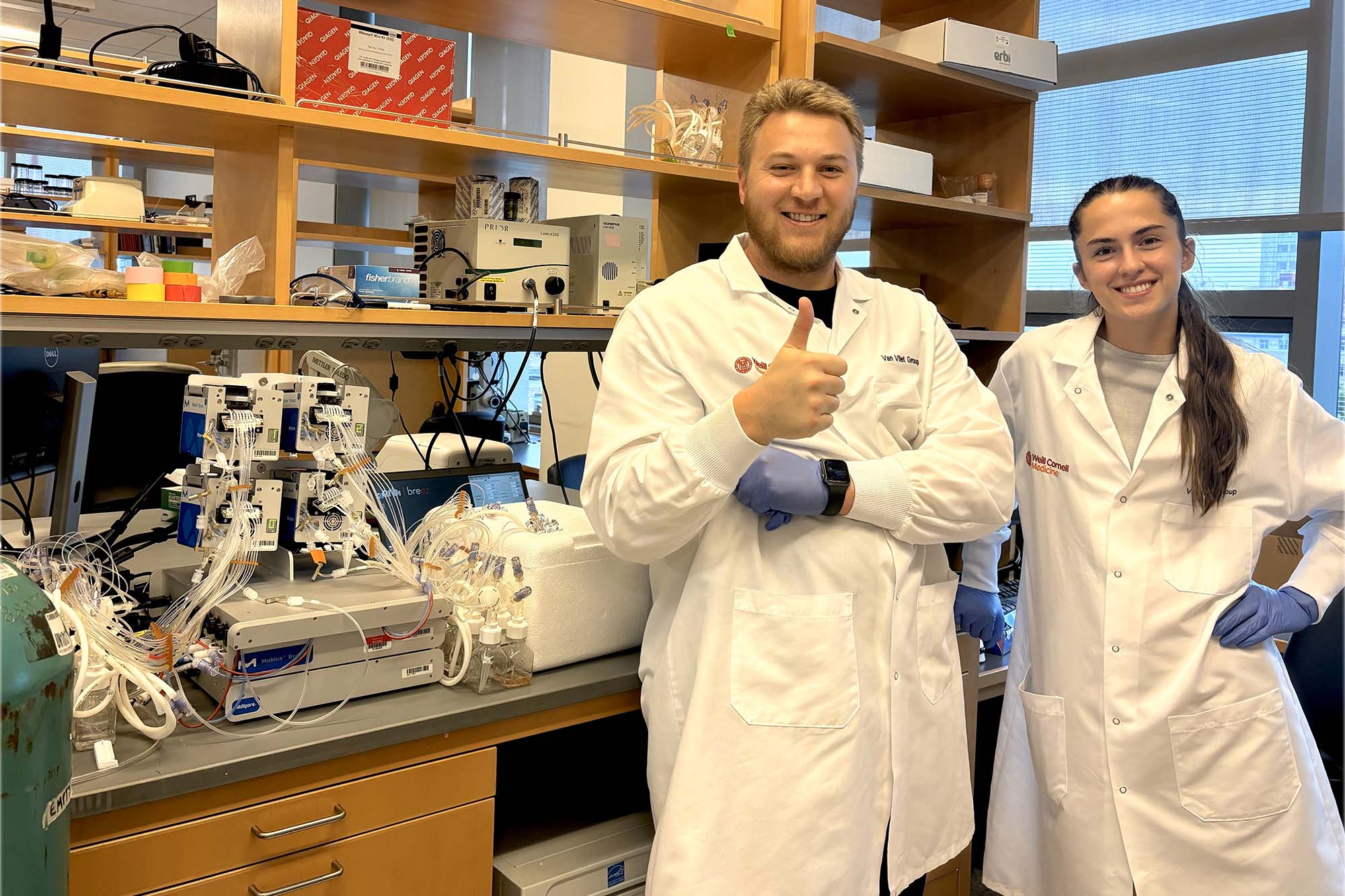 Van Vliet lab students in lab coats smiling and thumbs up.