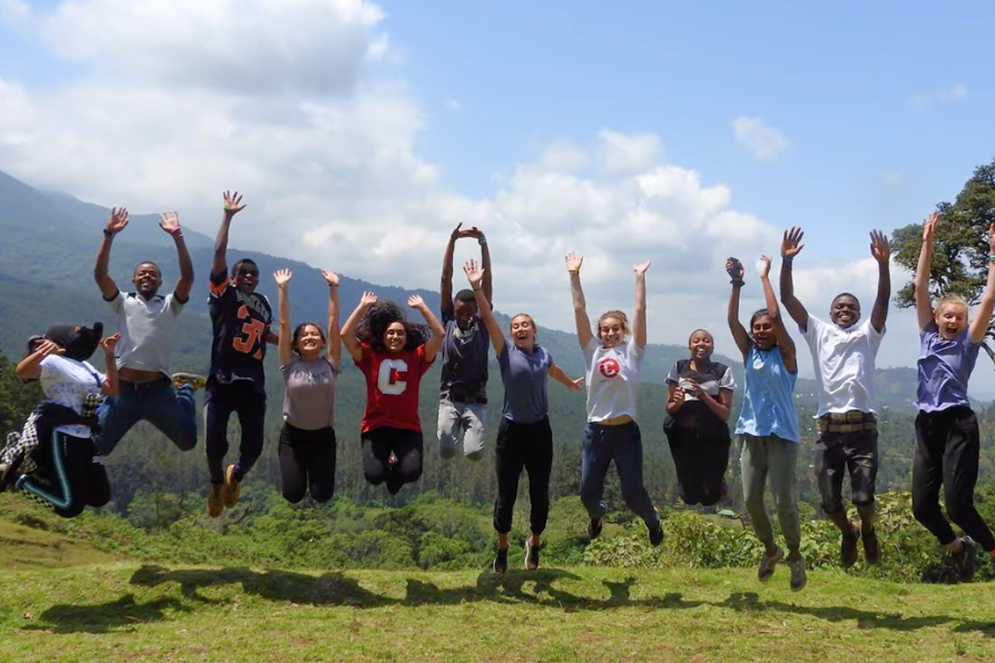 Undergraduate students jump together outside in Tanzania.