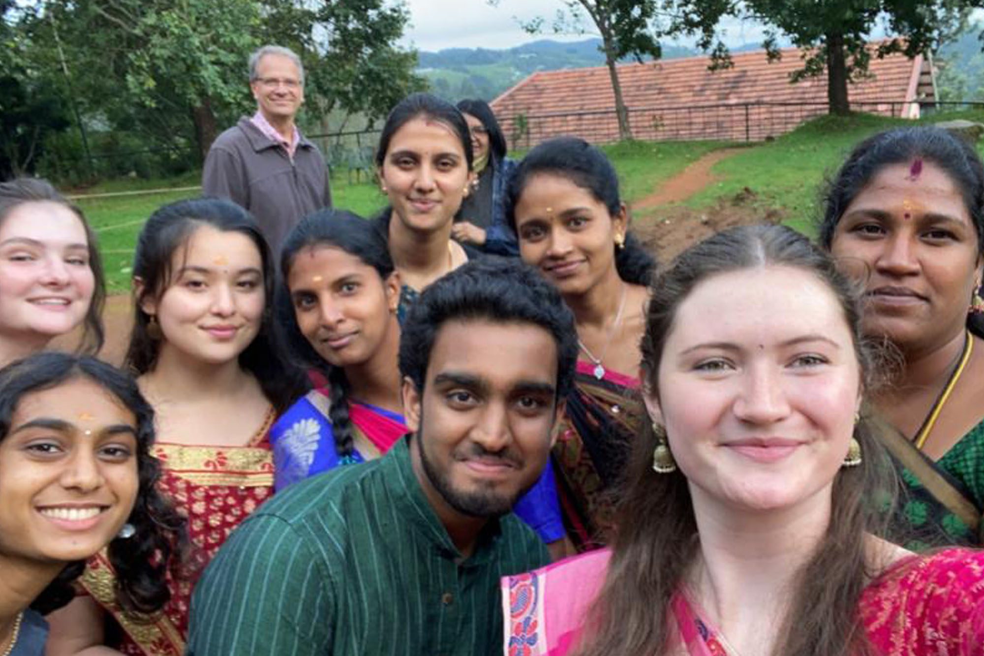 Undergraduate students wear saris with host family during study abroad experience.