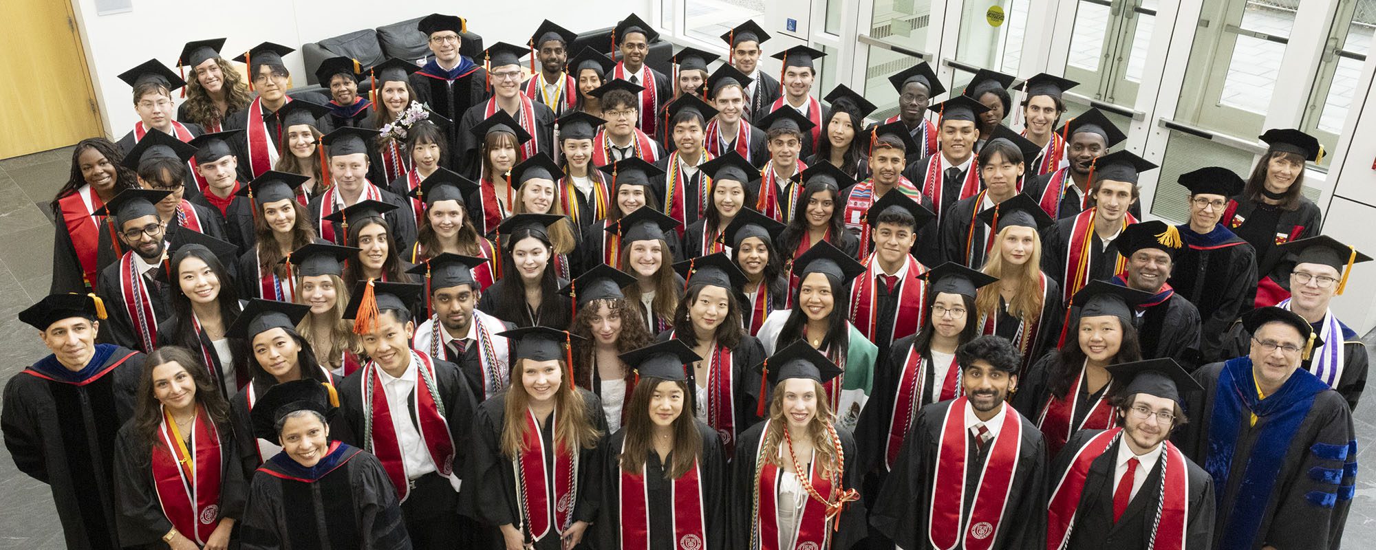 Undergraduate graduates standing together in Weill Hall atrium May 24 2025.