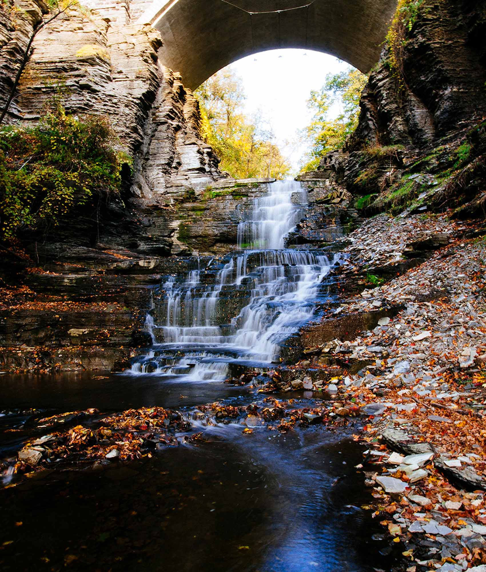 The Cascadilla Creek waterfall under the College Avenue Stone Arch Bridge, in fall.