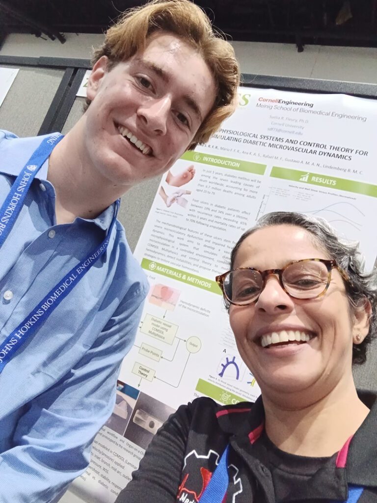 Ithaca High School junior Imri Wolf and Suelia Rosa smile in front of a conference poster.