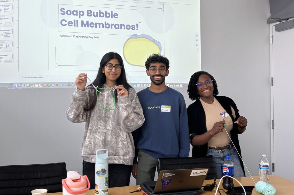 Three graduate students stand together presenting to girl scouts in Weill Hall for girl scout engineering day (GSED) 2025.