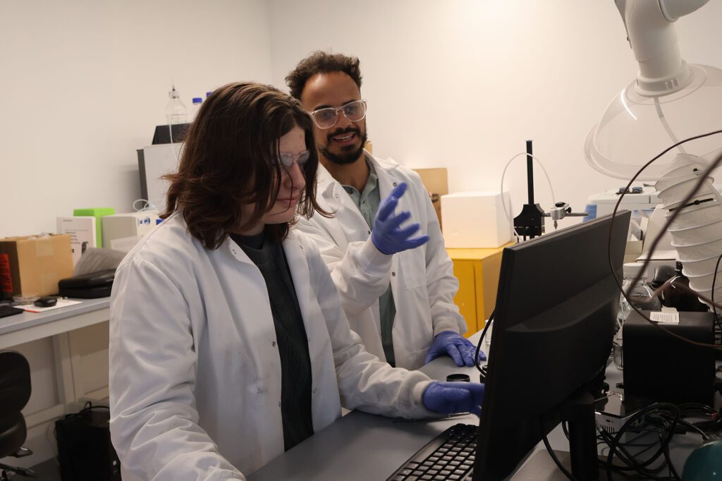 Stephanie Fingerman (junior, chemical engineering) and Jeremiah use the goniometer to measure surface energy a critical parameter in condensed droplet polymerization (CDP).