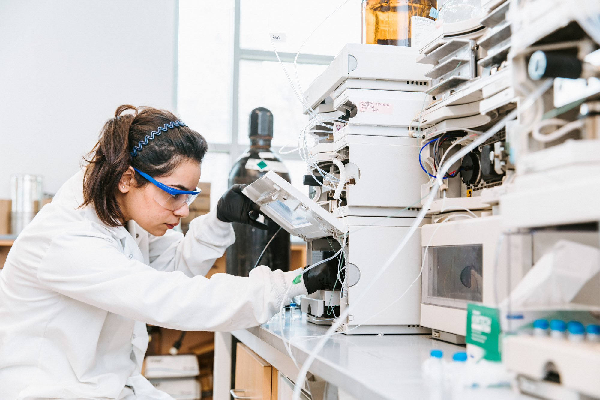 a student in a lab coat working on an experiment in the Alabi Lab