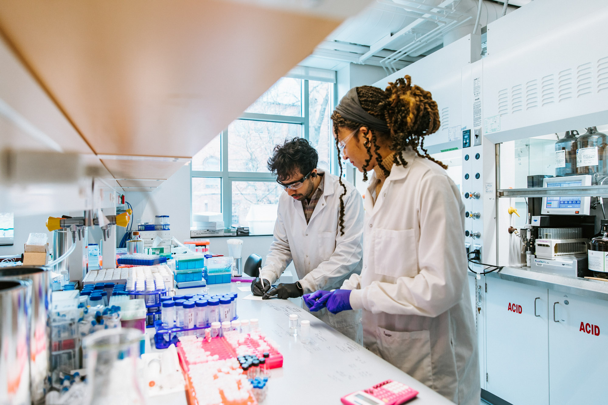 two researchers in lab coats conducting an experiment in the Alabi Lab.
