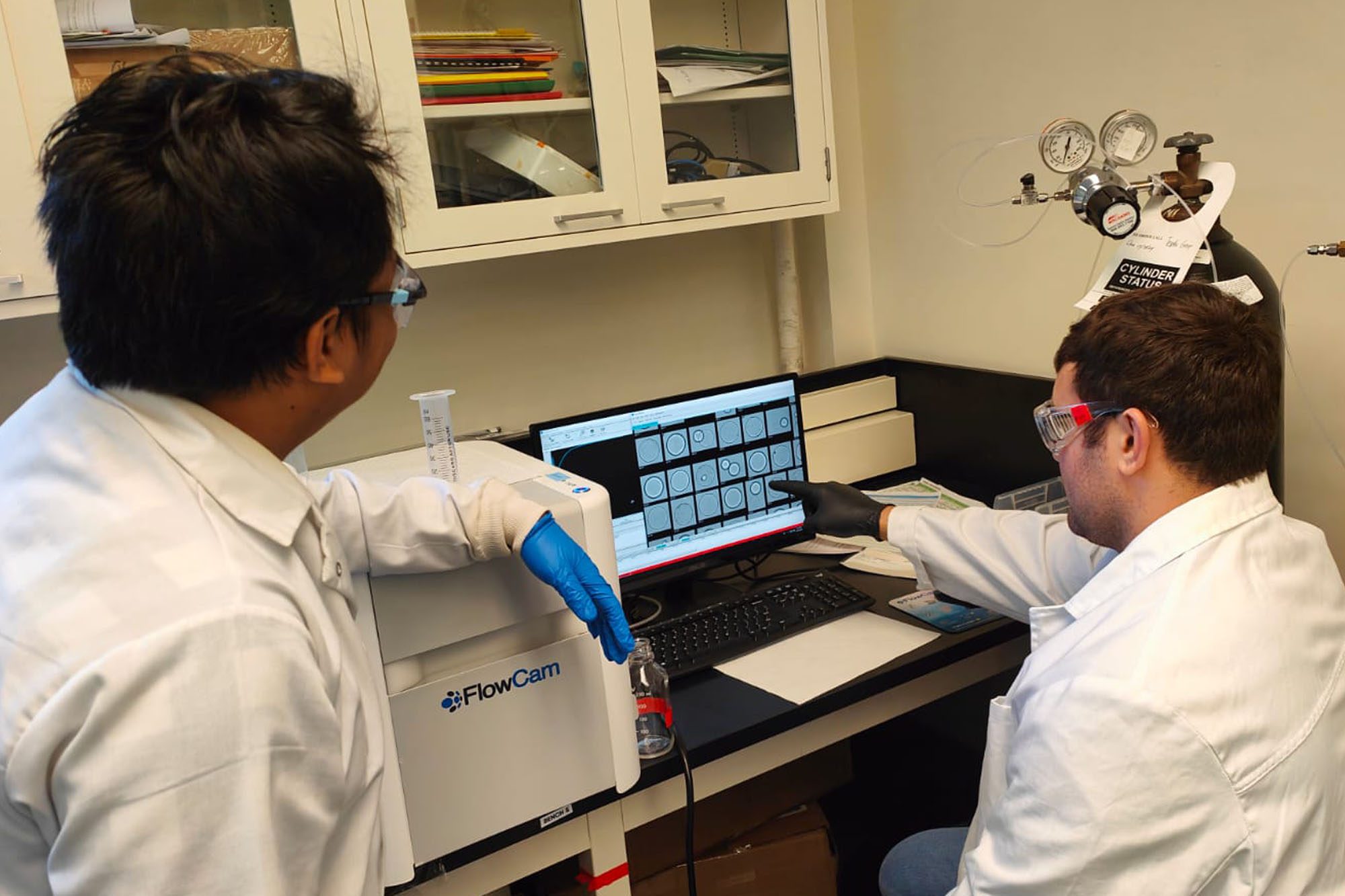 Tester lab students discuss sustainable energy research imaging on computer.