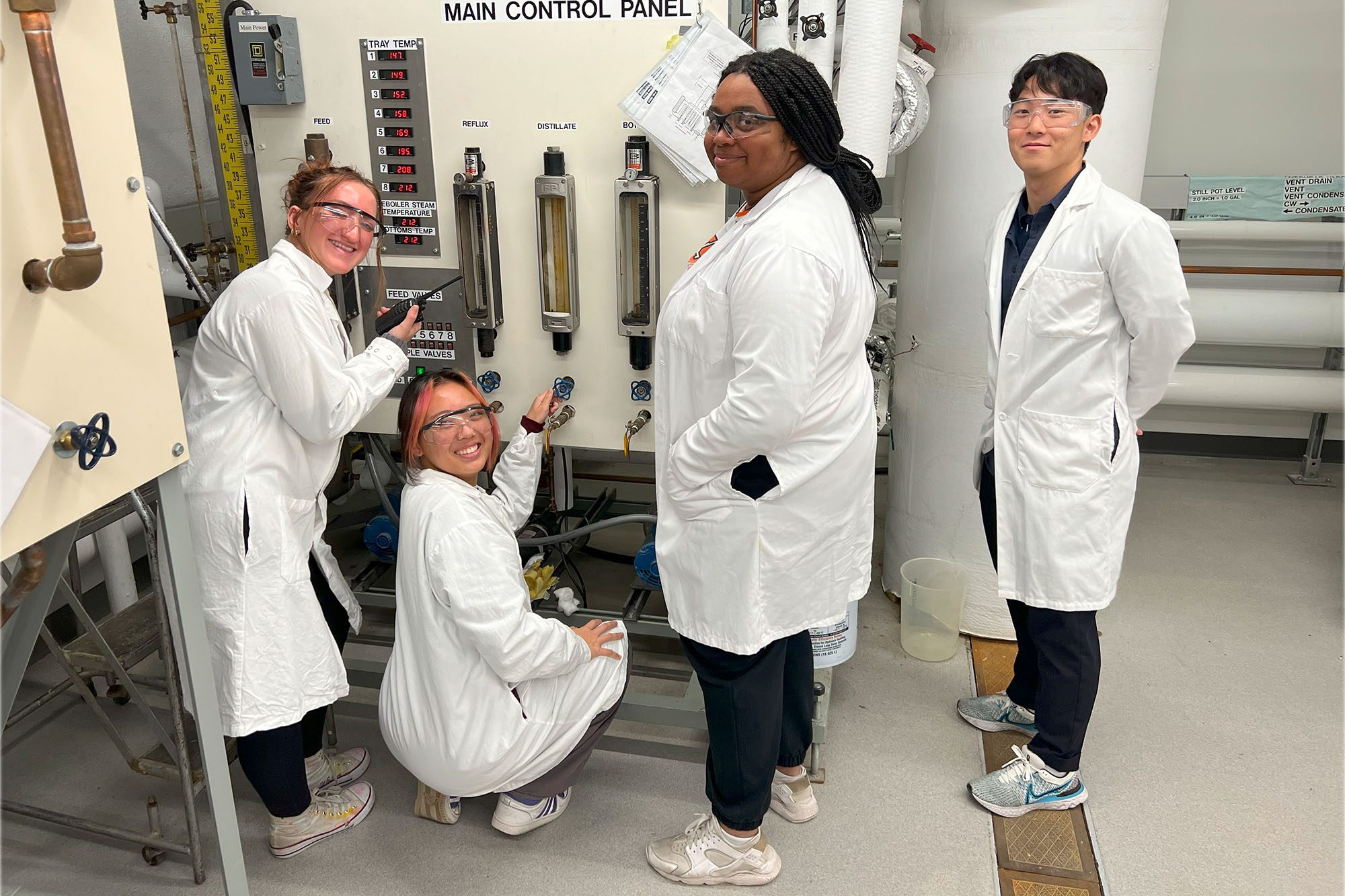 Undergraduate students in active learning initiative ALI stand in lab coats with equipment.