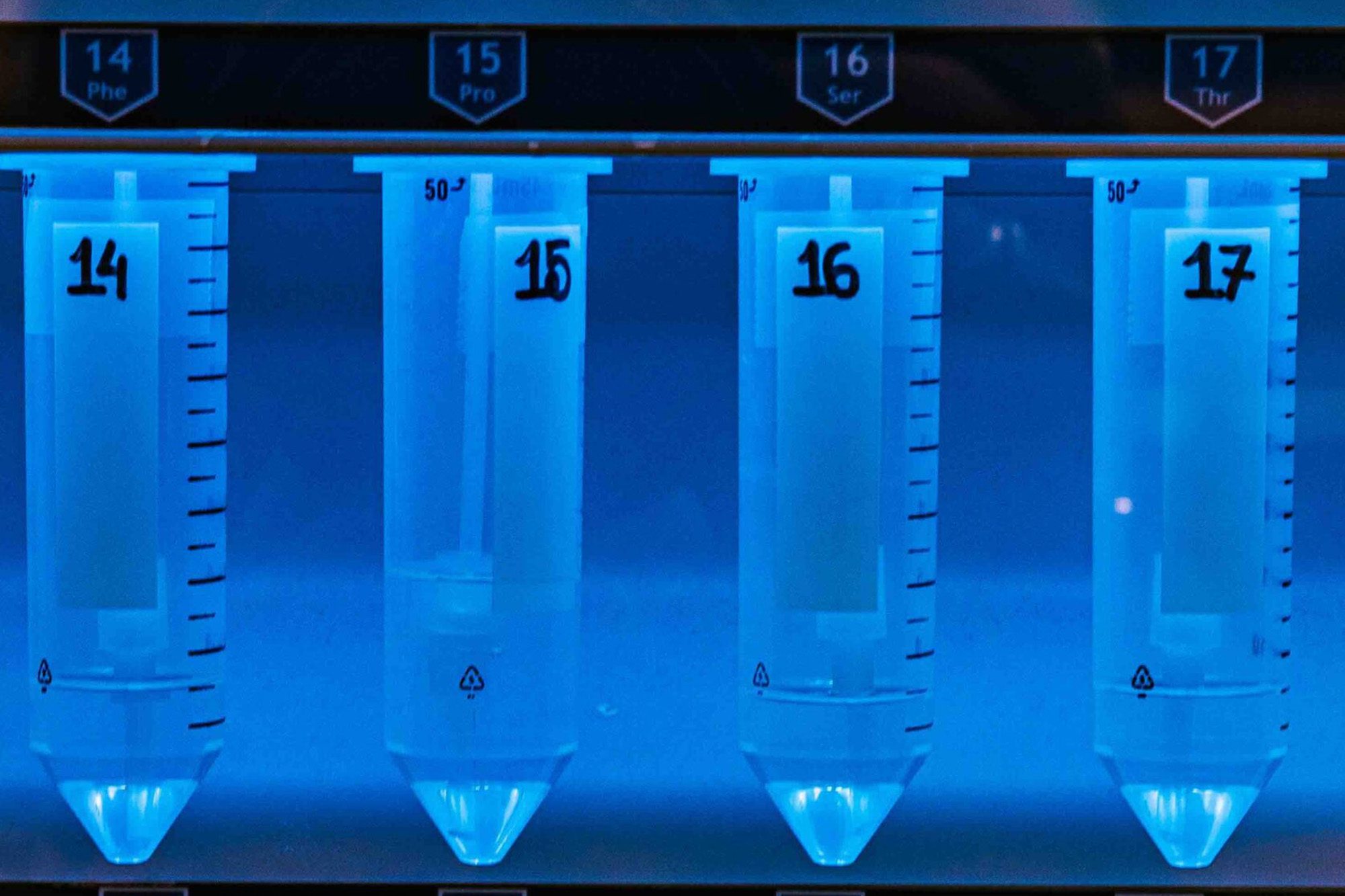 A line of illuminated liquid-filled tubes for biomolecular testing lined up in a fume hood.