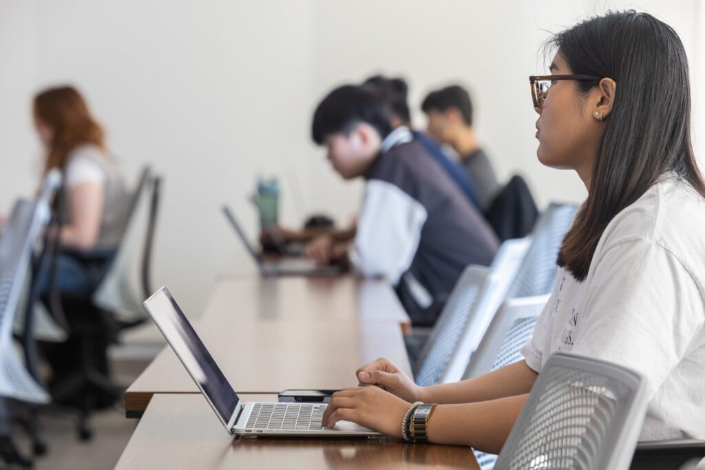 MEng student sits with laptop in Upson Hall design class with Jeff Varner.