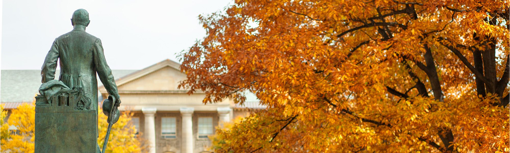 The statue of Ezra Cornell on the Arts Quad in fall.