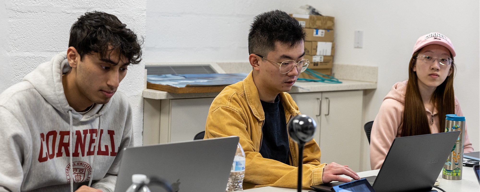 MEng Students work at table with laptops on their immersive capstone project.