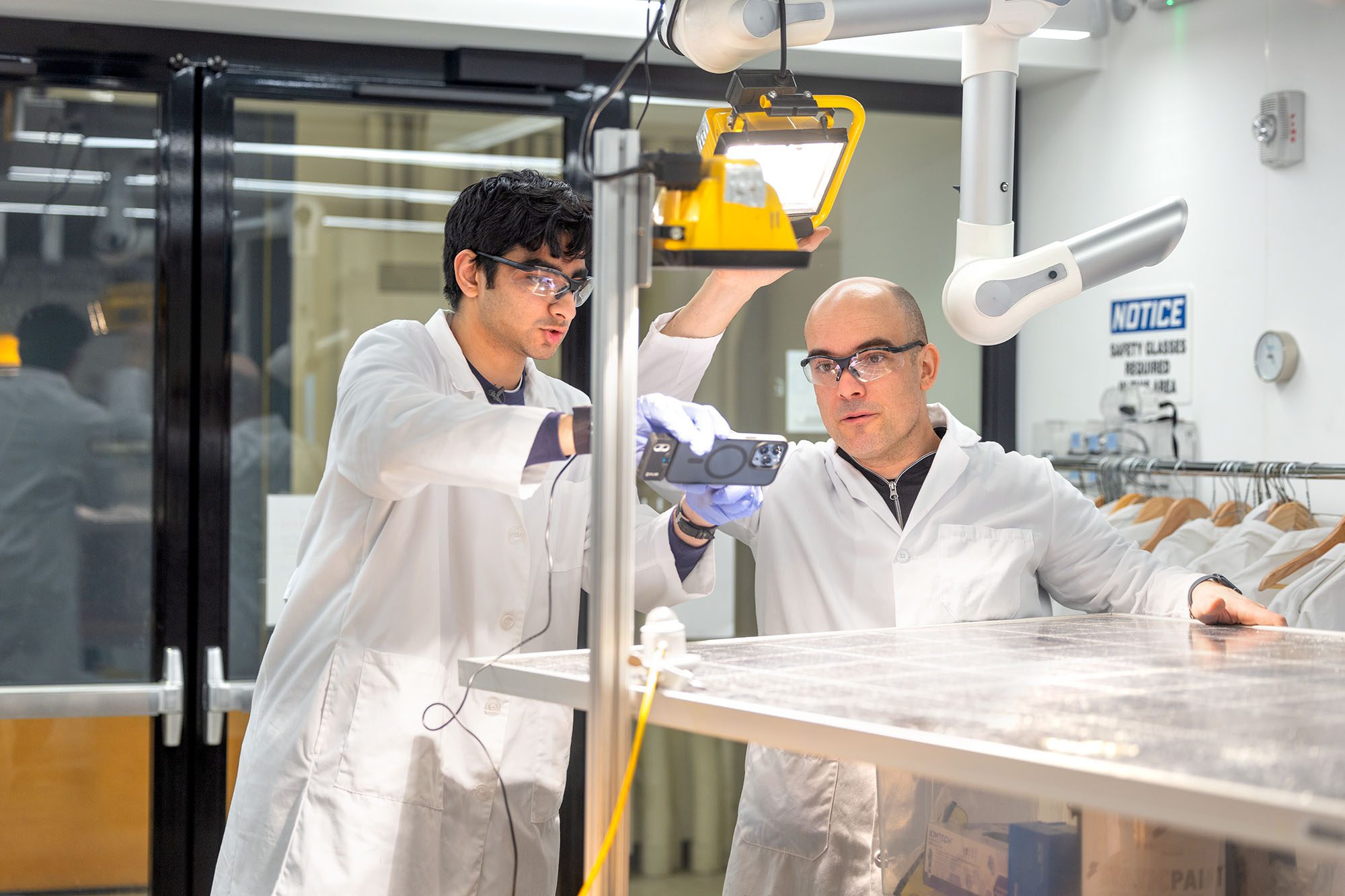 Materials science and engineering major Aarav Seth ’25 (left) and Tobias Hanrath, the David Croll Professor of Engineering, apply a package containing phase-change materials that can reduce the operating temperature of a PV module by an average of 5.2 degrees Celsius