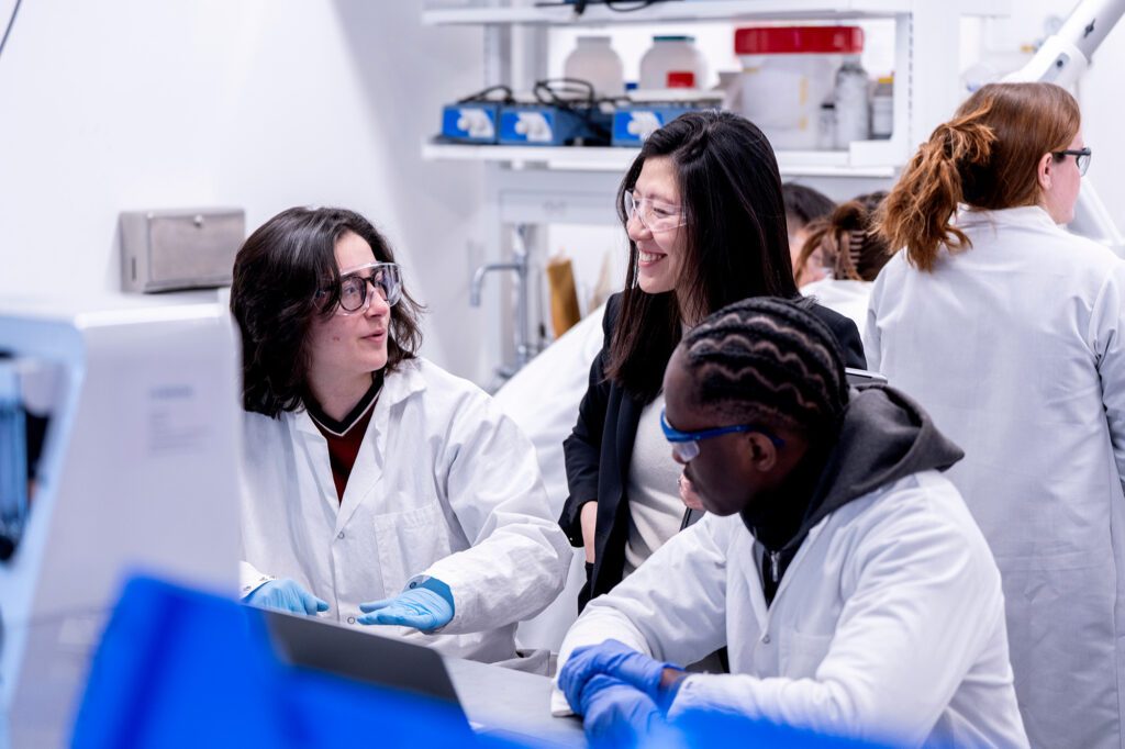 Rong Yang with students wearing lab coats in Olin Hall.