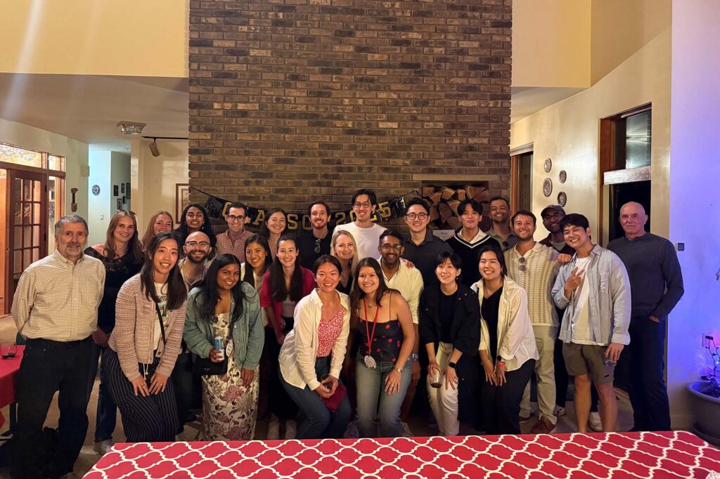 Faculty and alumni stand together in front of stone fireplace.