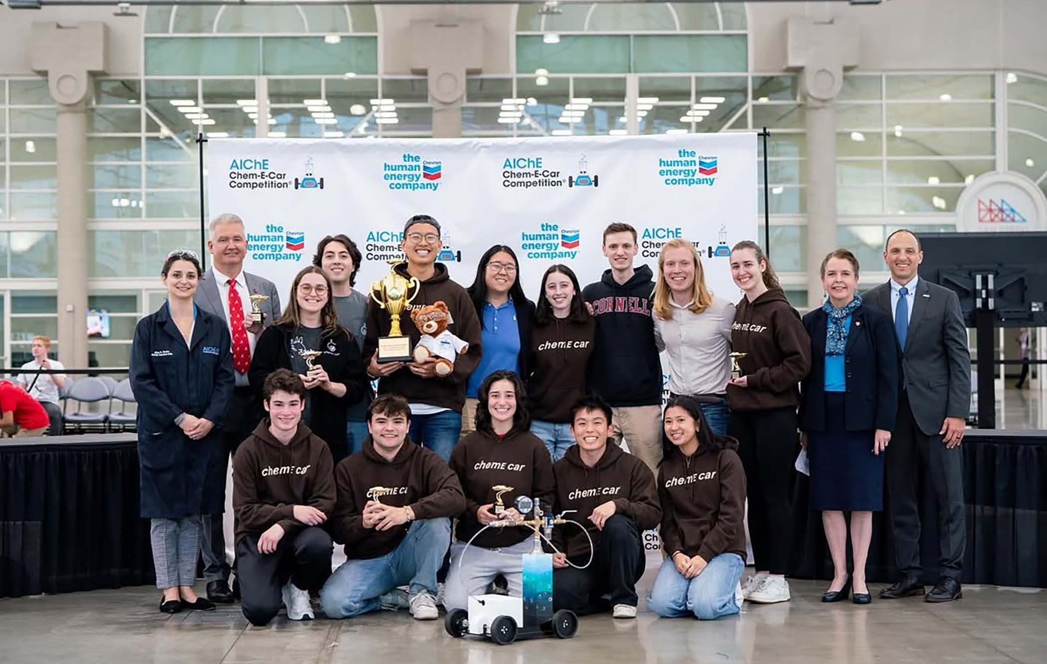 The ChemE car team of undergraduates stand together with competition leadership.
