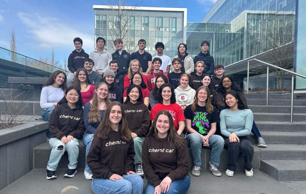 The ChemE car team of undergraduates sit together outside on steps.