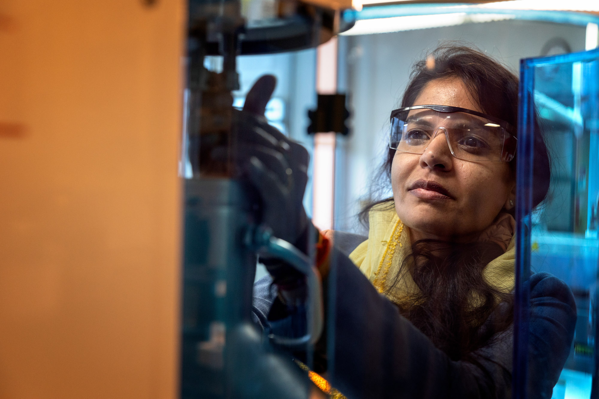 Greeshma Gadikota wearing safety glasses while operating a machine in a lab