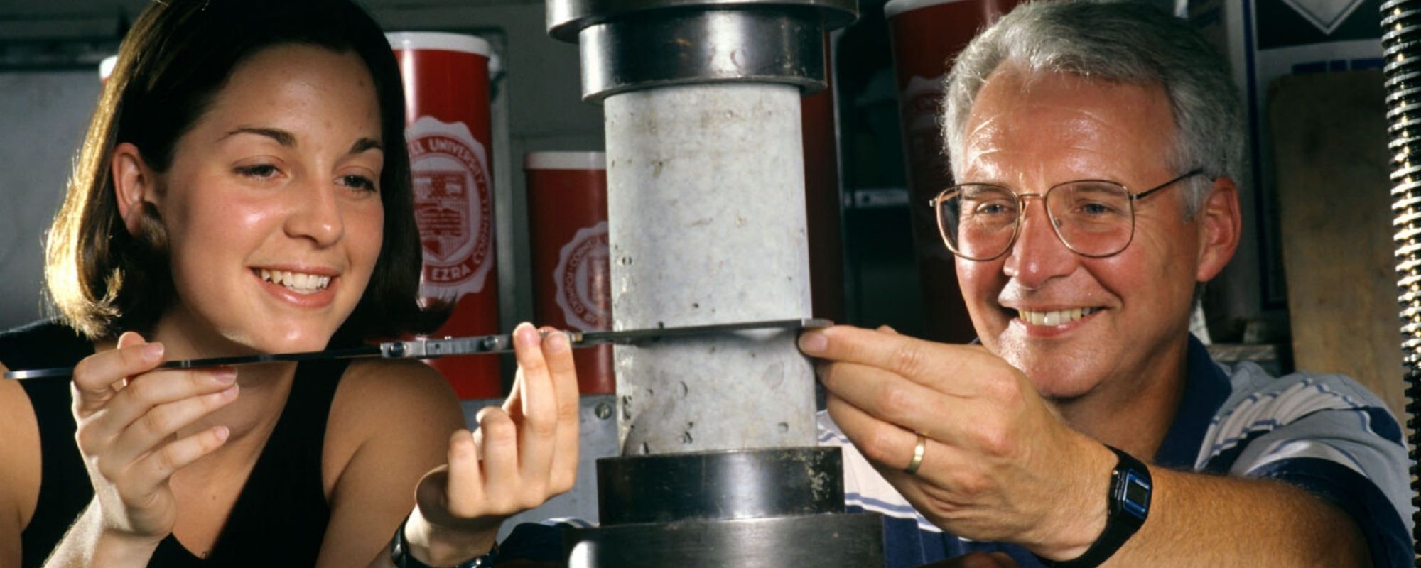 Kenneth Hover with student measuring a concrete cylinder in a lab