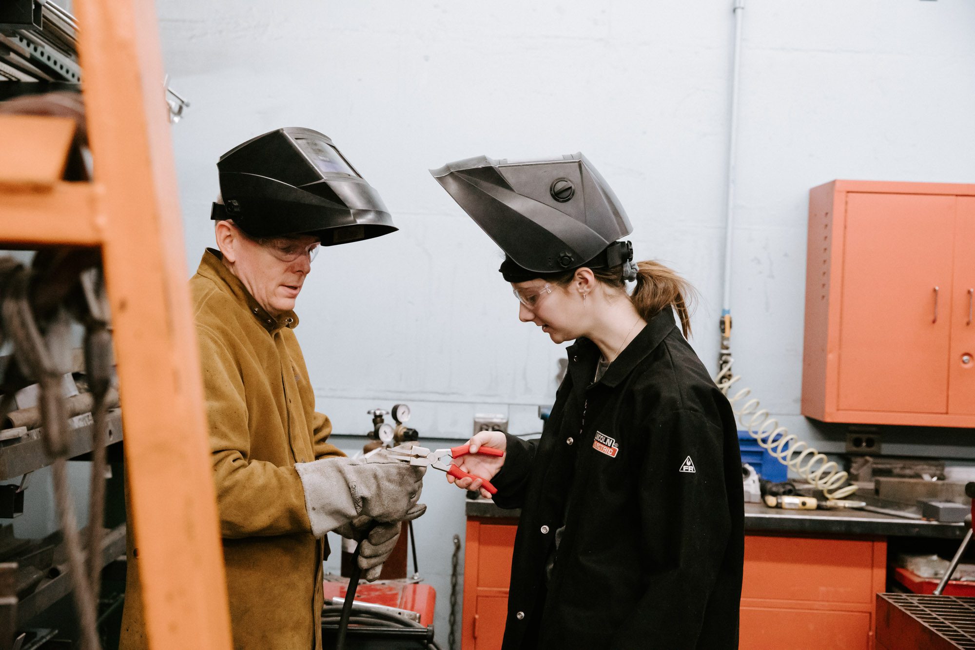 Researchers wearing dark helmets and protective clothing study equipment