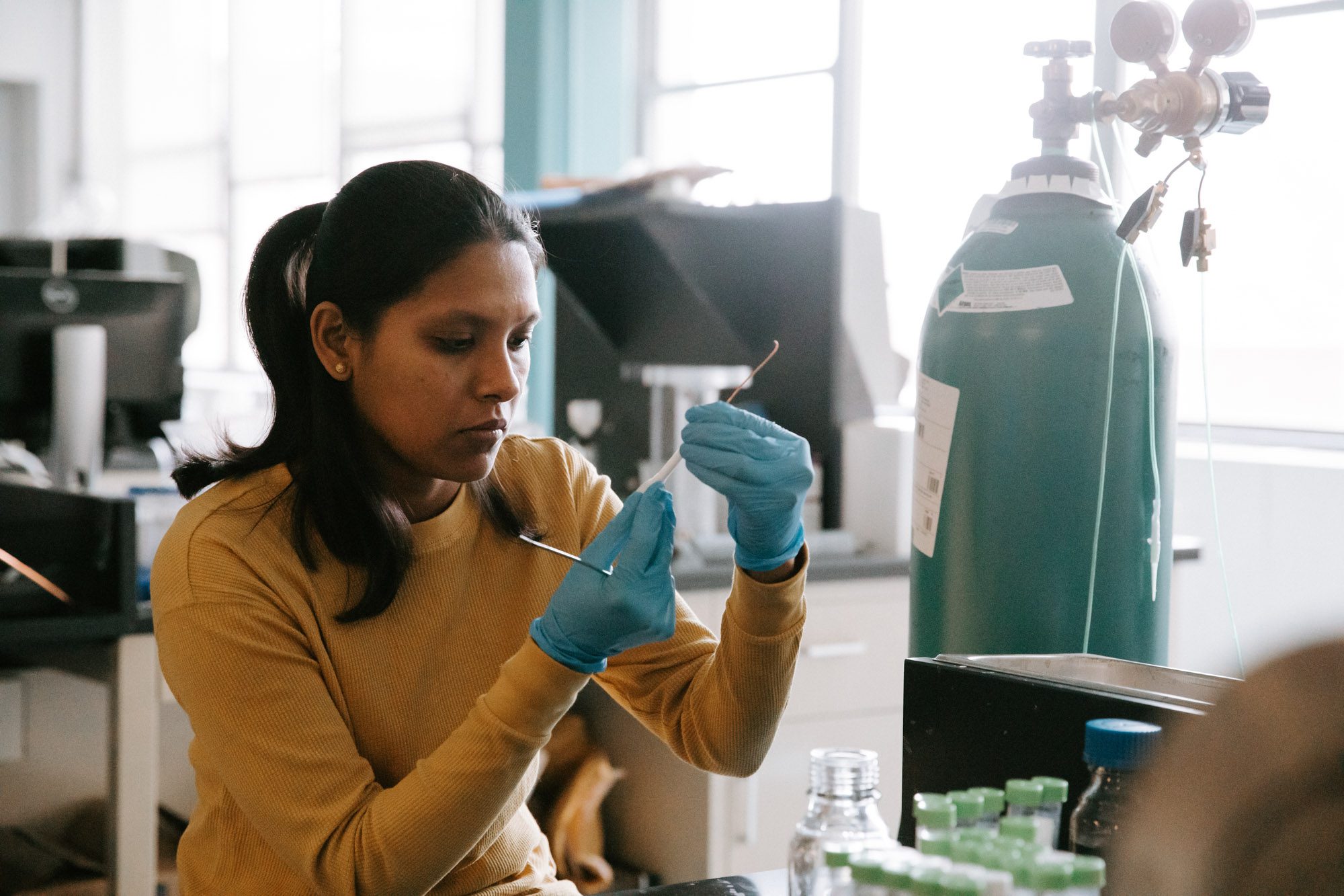 Student wearing protective gloves holds up and observes measuring device