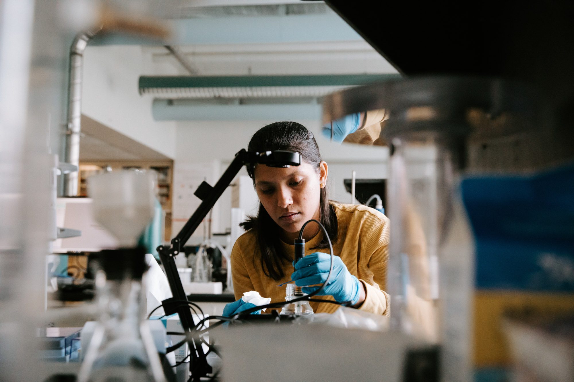 Student wearing protective gloves works with device