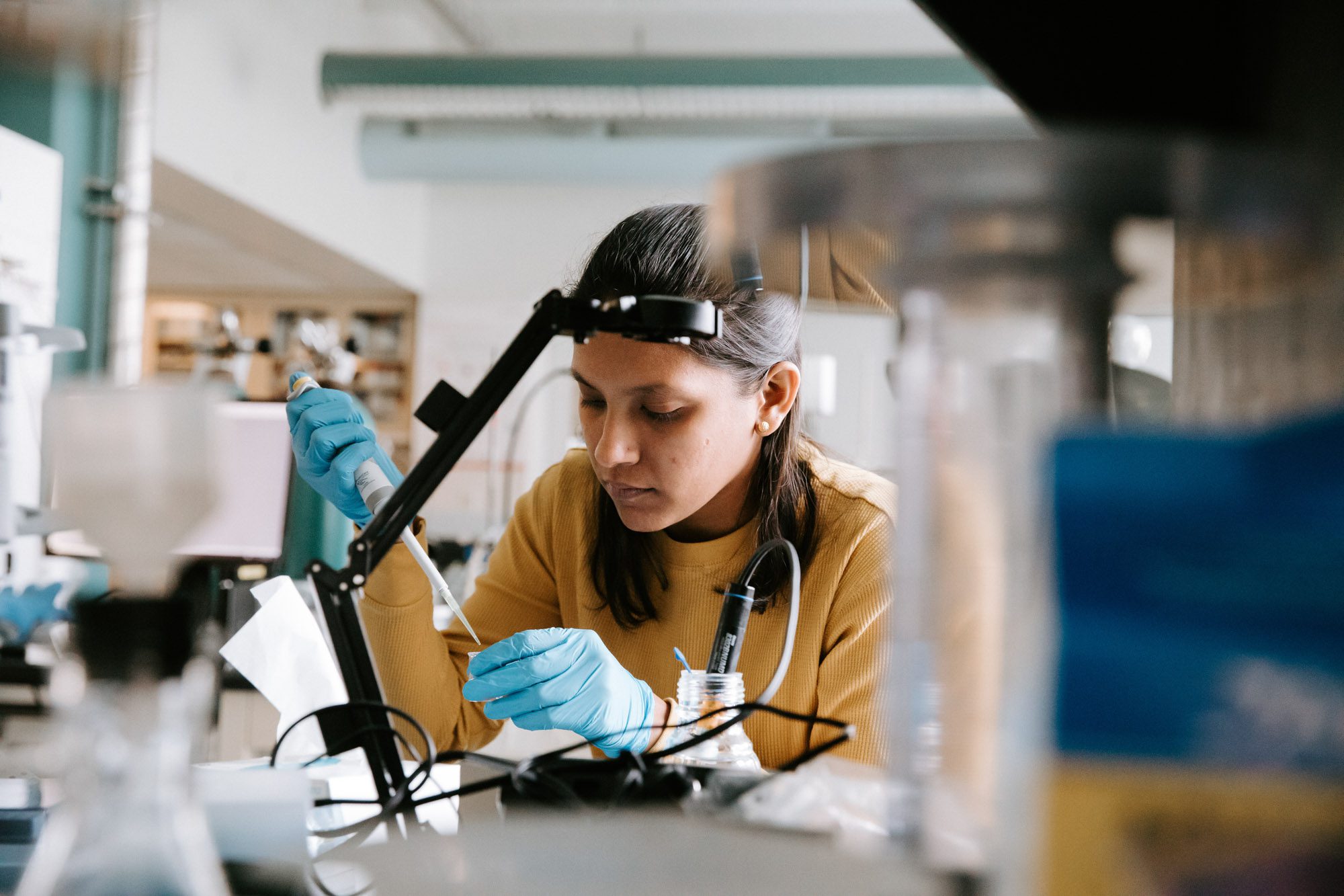 Student wearing protective gloves works with device