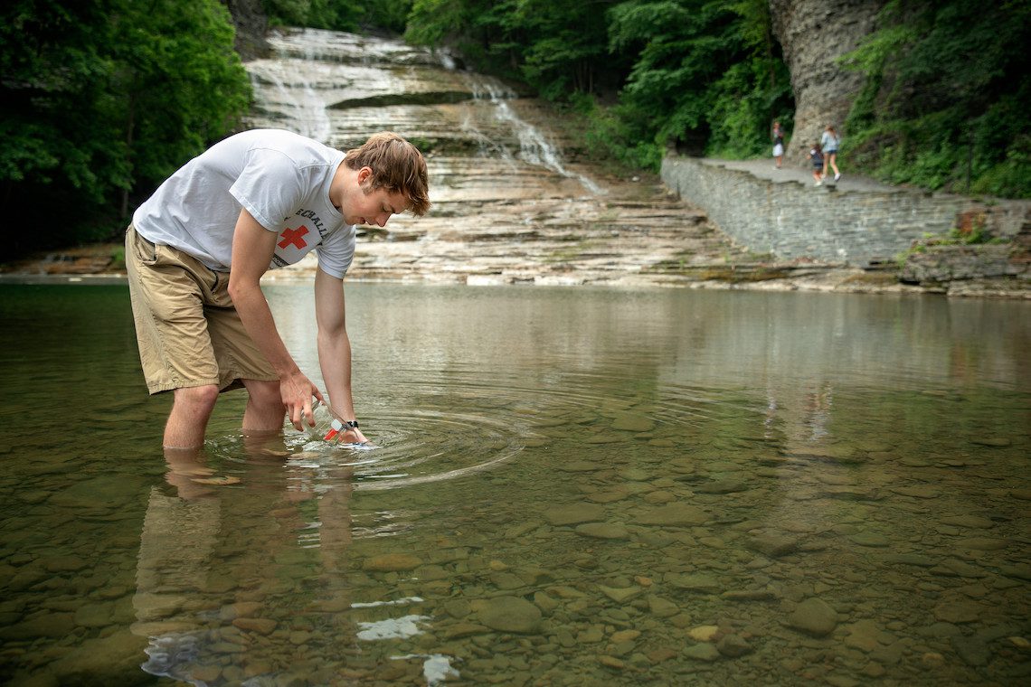 student dips hand in water