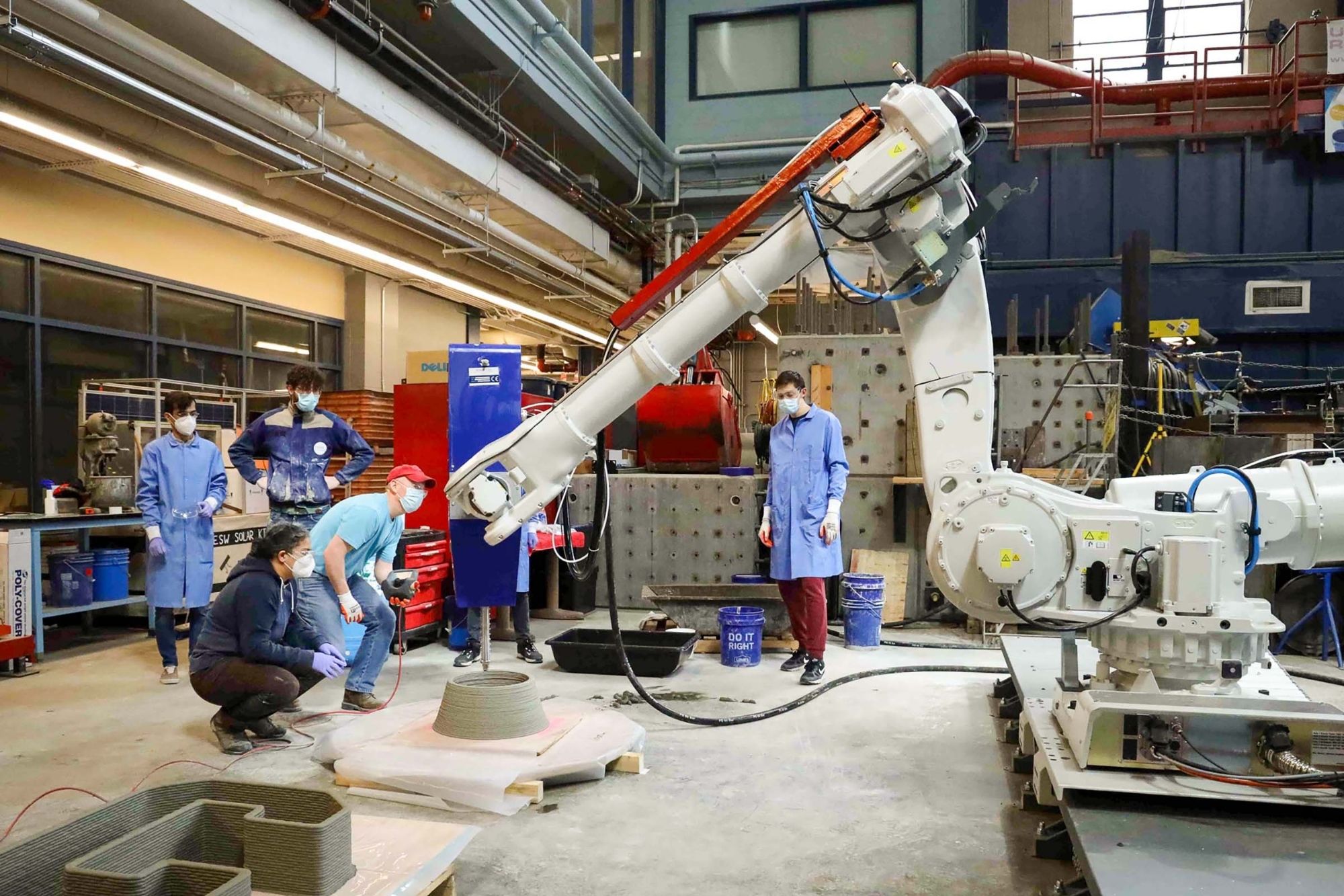 Students and faculty surround large robot pouring concrete in Bovay lab