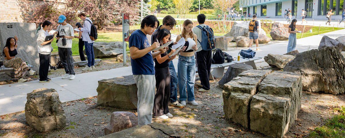 Students in the Pew Engineering Quad rock garden, looking at rocks and taking notes.