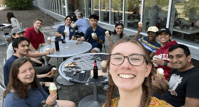 Students and faculty seated outside of Cornell Dairy, smiling and eating ice cream.