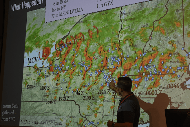 Man stands in front of a slide showing a weather radar map of upstate NY. He is pointing at the map.