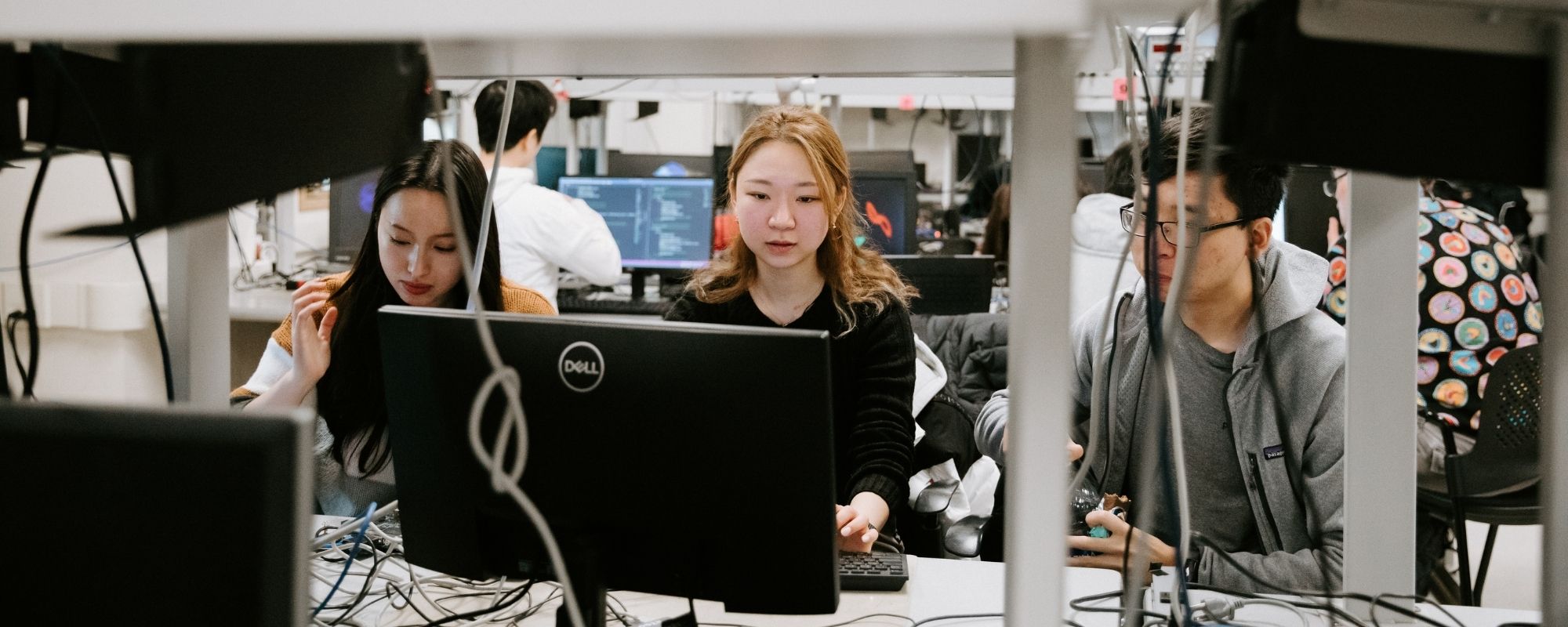 Students working in a computer lab with wires and monitors all around them