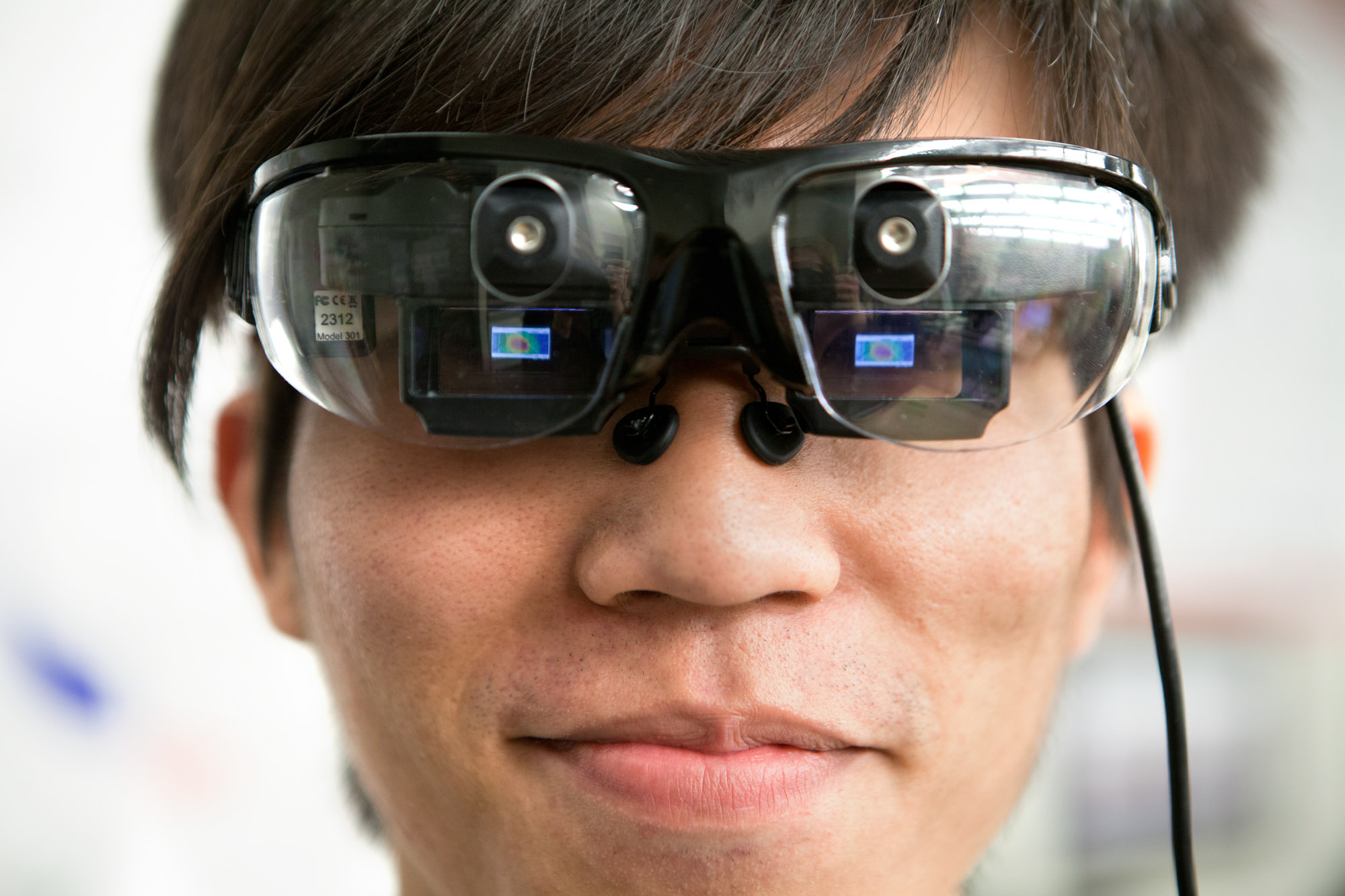 Close-up of a man wearing a pair of glasses that mirror a computer screen.