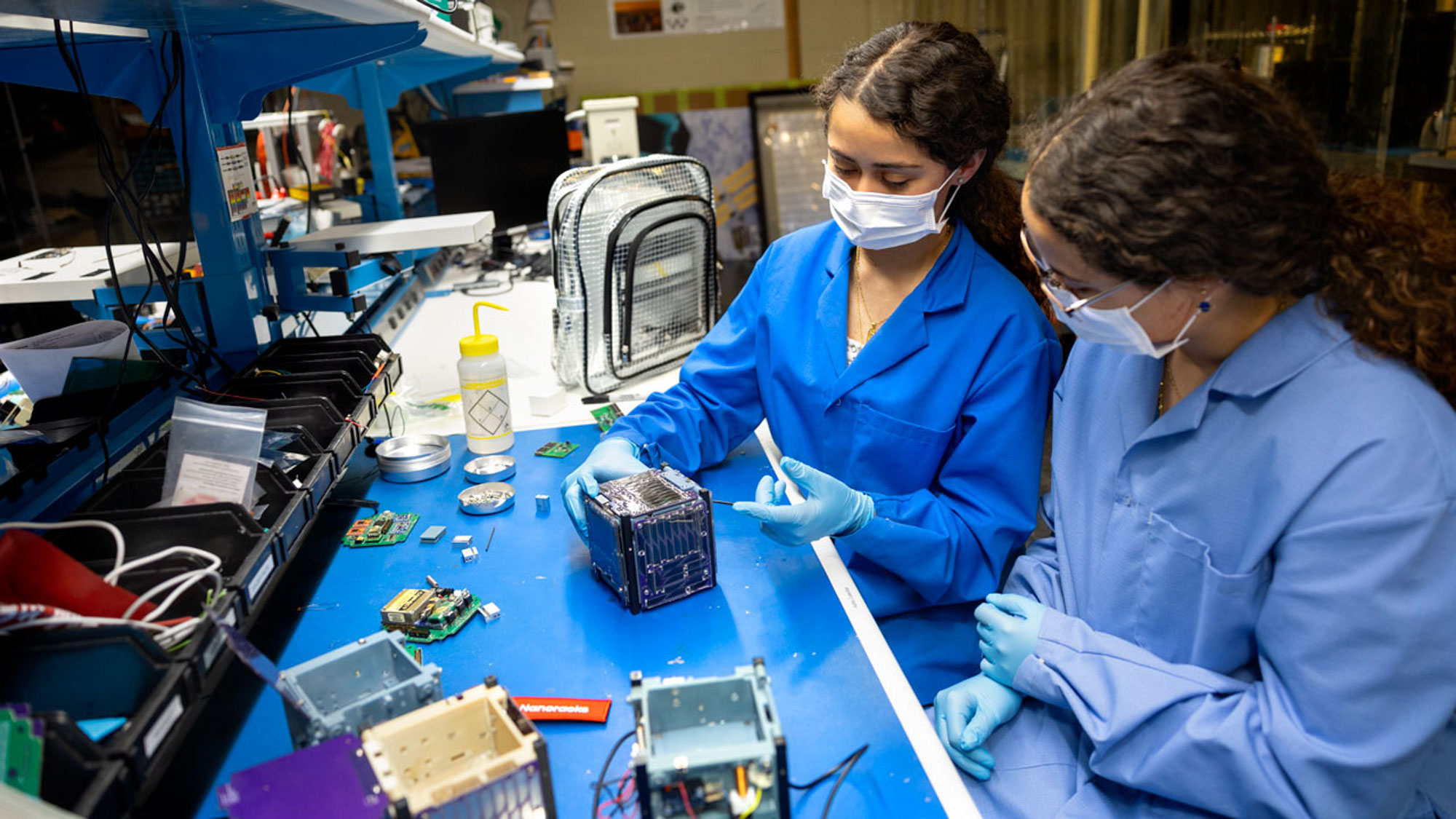 Twin sisters and mechanical engineering majors Verena (L) and Ashley (R) Padres in the Space Systems Design Studio Lab. She is showing Alpha CubeSat (light sail-carrying, cube-shaped satellite)
