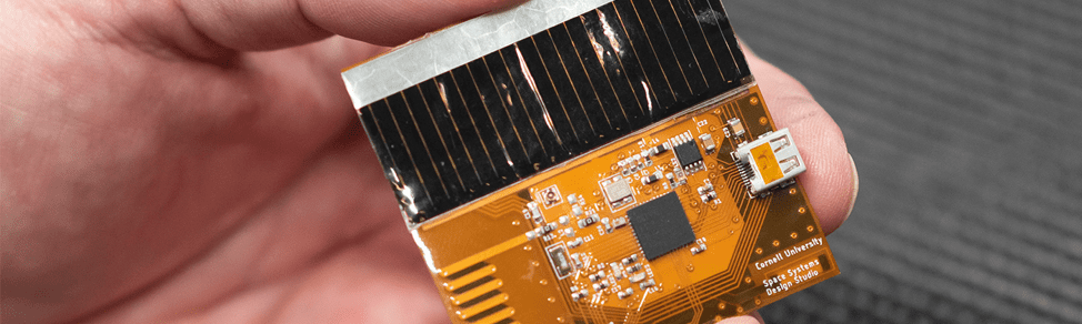 close-up of a hand holding a yellow and black chipsat.