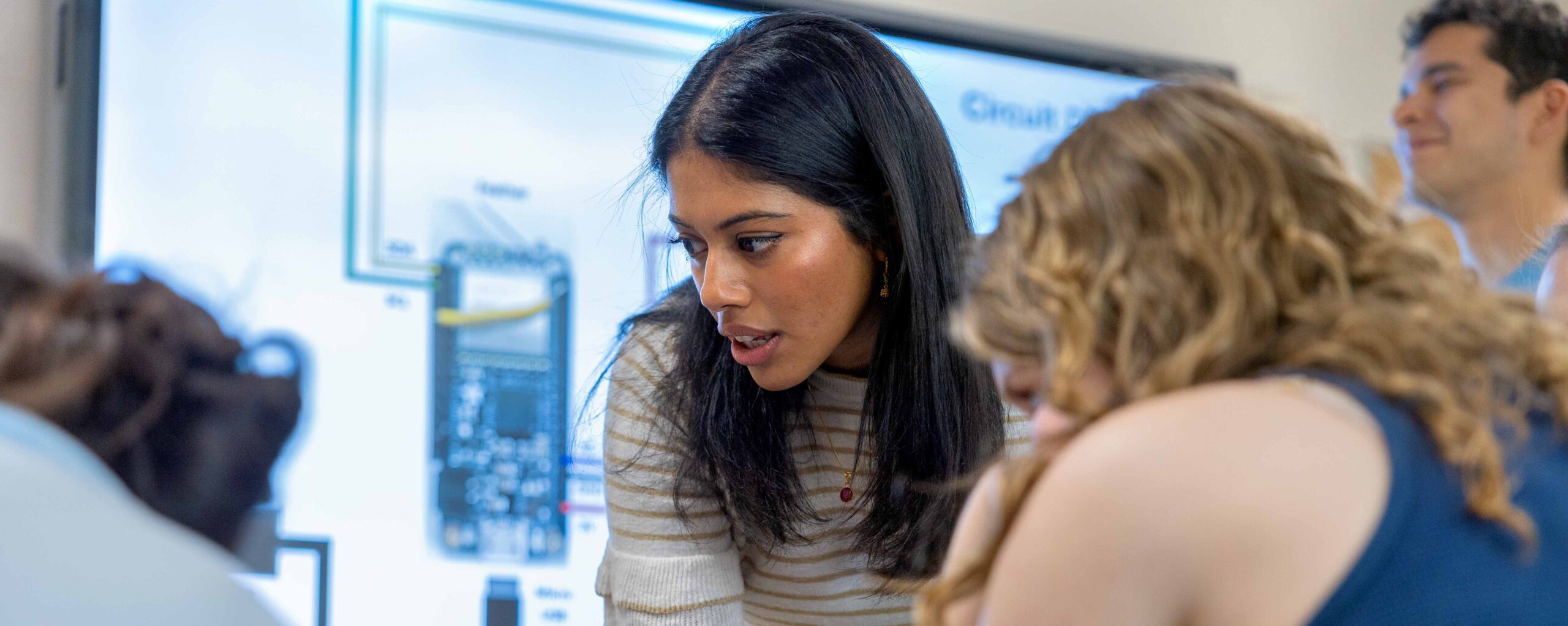 M.Eng. student looking at monitor with other student, as part of Max Zhang Class Internet Of Things at Geneva High School