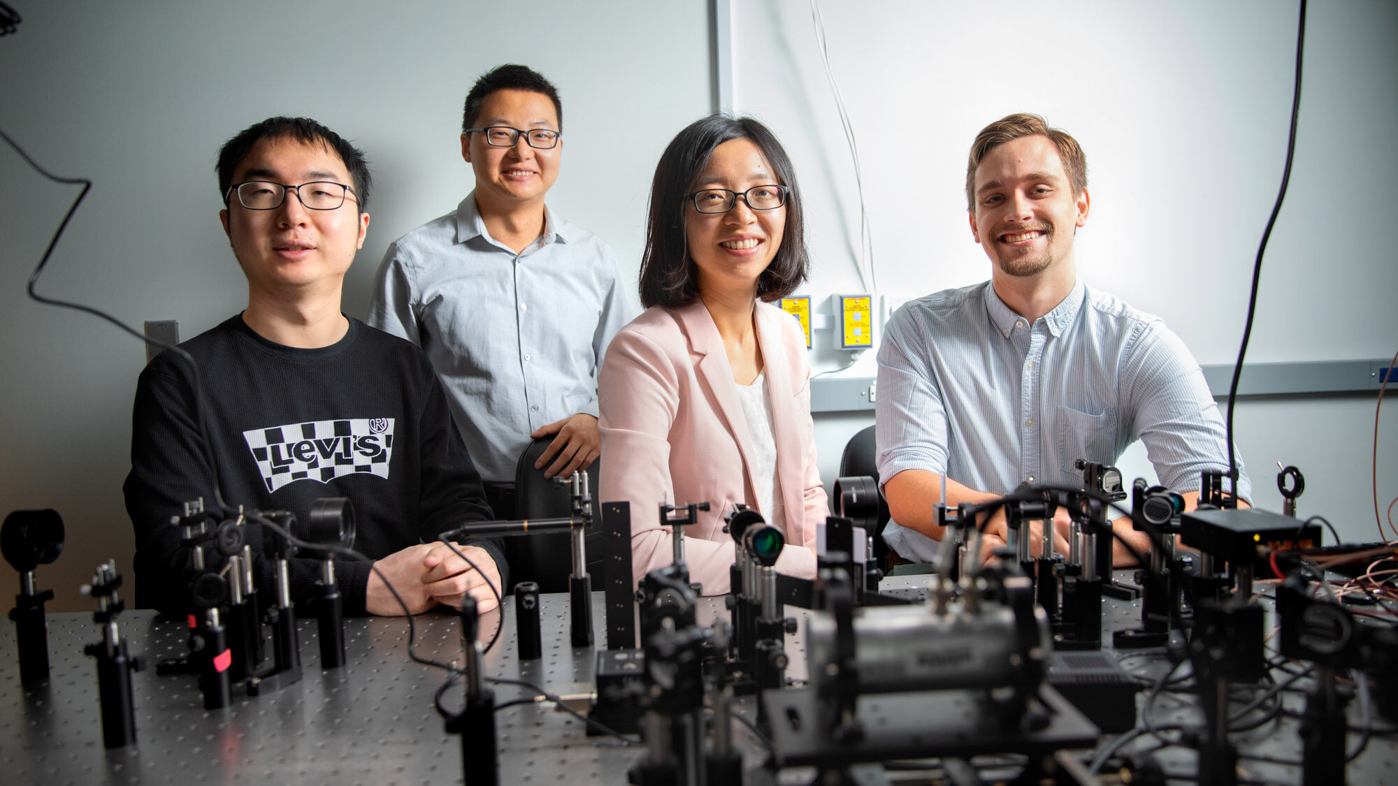 Zhiting Tian and some members of her lab pose in front of some lab equipment.
