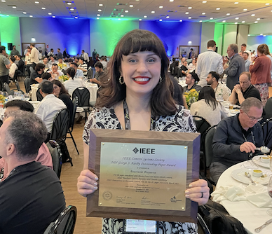 Anastasia Bizyaeva holds a plaque from the IEEE recognizing her Axelby Award.
