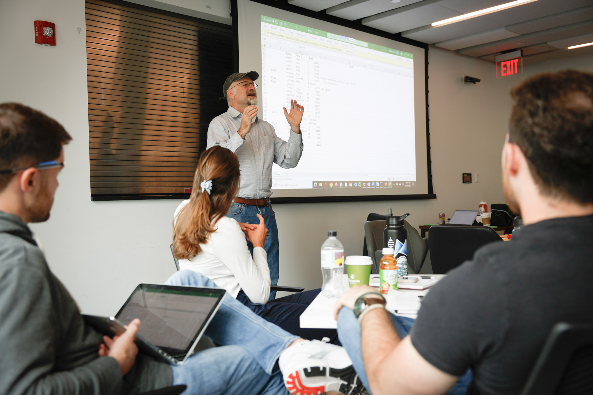 Professor giving presentation to students sitting at small tables during their residential experience