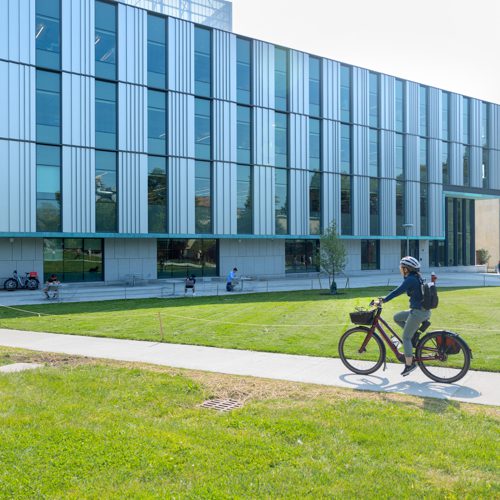 A student riding a bike outside of Tang Hall