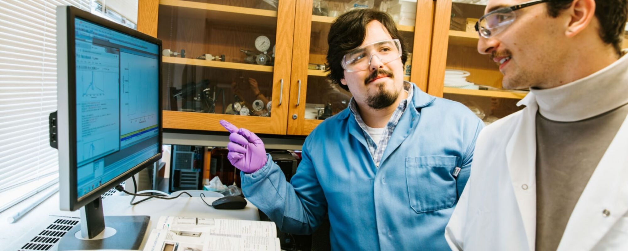 Two graduate students looking at a computer monitor in associate professor Richard Robinson's research lab