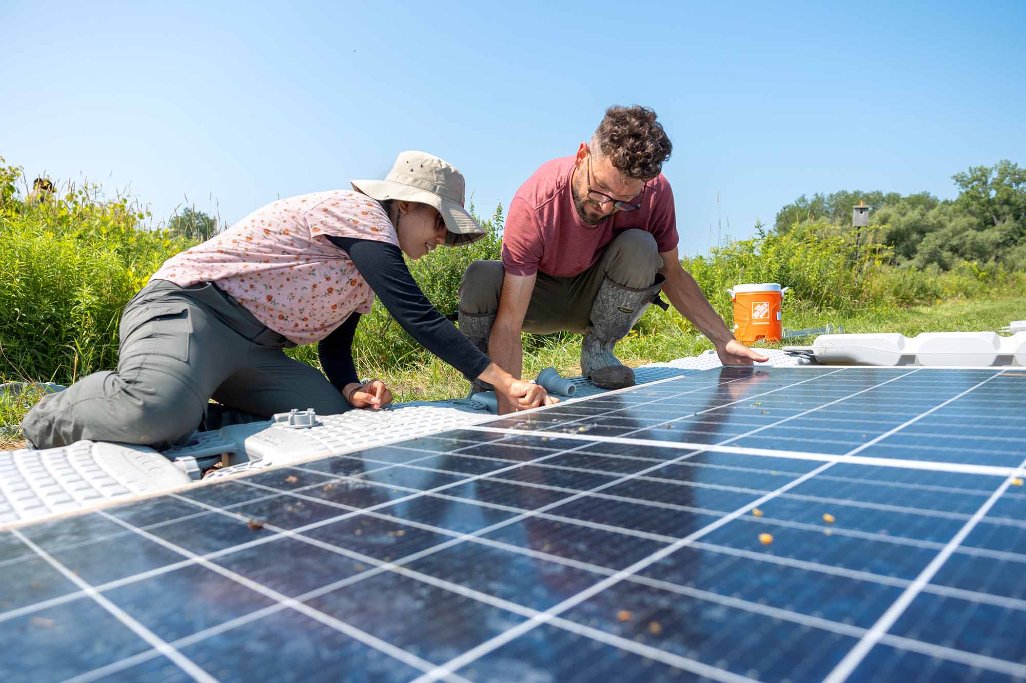 Two people work outdoors on solar panels