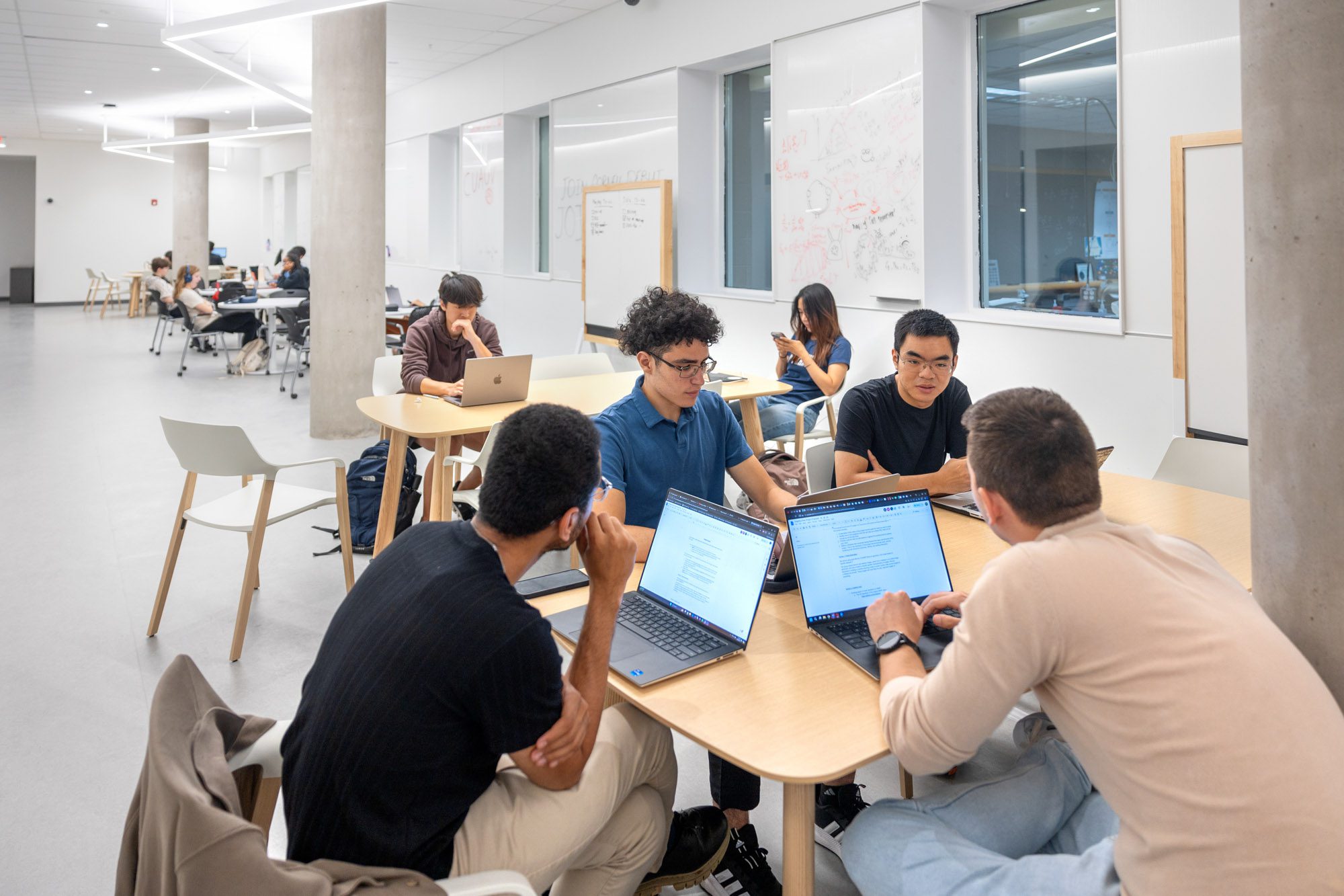 Students gathering at tables in the common study space in Tang Hall.