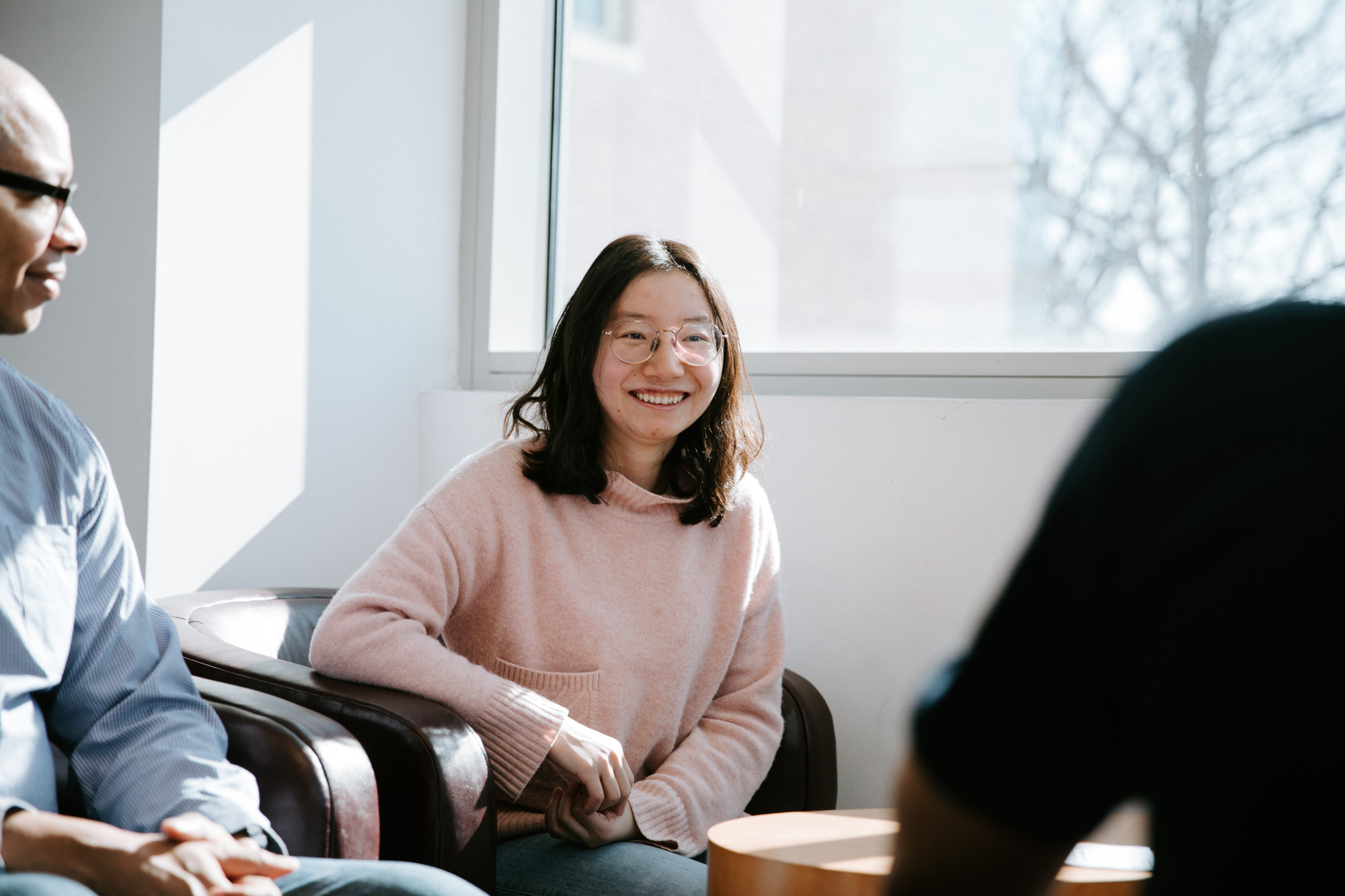 ORIE Professor Mark Lewis seated in Rhodes Hall as two seated students talk.